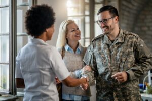 Happy veteran and his wife greeting African American doctor at medical clinic.